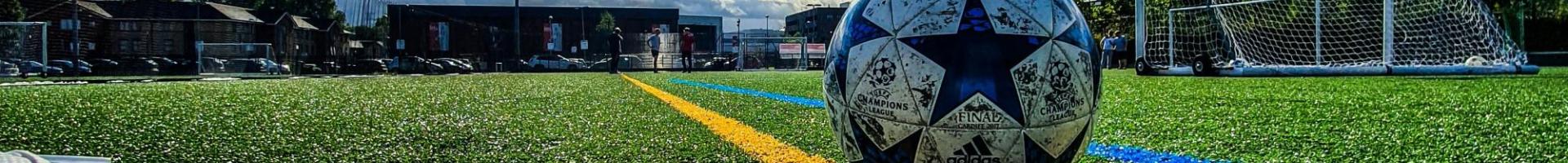 A picture of a soccer ball pitch. Soccer ball, green turf and shoe